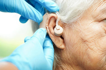 doctor helping an elderly patient put on hearing aids